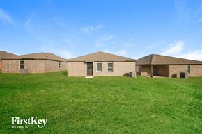 Tuttle house for rent - A grassy field with three houses and a blue sky.