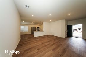 Tuttle house for rent - A spacious room with wooden floors and a kitchen area in the background.