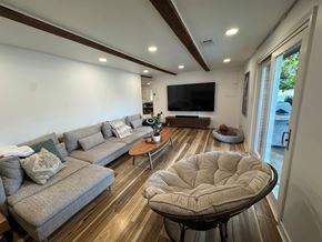 Louisville house for rent - A modern living room with a grey sofa, a round ottoman, and a flat screen TV mounted on the wall.