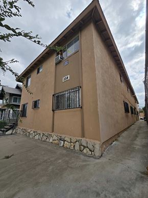 Los Angeles apartment for rent - A tan building with a stone foundation and a black iron fence.