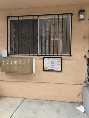 Los Angeles apartment for rent - A window with a metal grill and a sign on the wall.