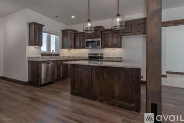 Victor house for rent - A kitchen with dark wood cabinets and a white countertop.