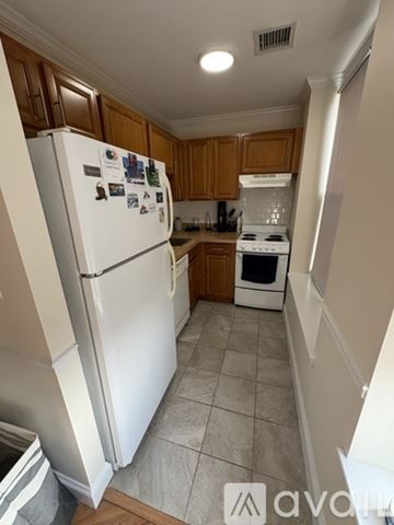 Boston apartment for rent - A kitchen with a white fridge and wooden cabinets.