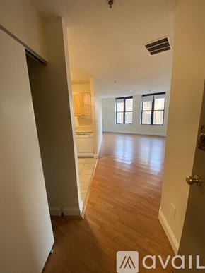 Boston apartment for rent - A hallway with wooden floors and white walls leading to a kitchen area.