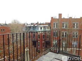 Boston apartment for rent - A balcony with a metal railing overlooks a courtyard with a building in the background.