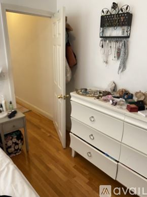 Boston apartment for rent - A white door is open to a room with a white dresser and a wall hanging.