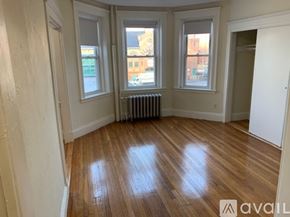 Boston apartment for rent - A room with wooden floors and three windows.