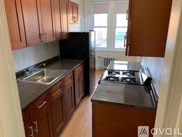 Boston apartment for rent - A kitchen with brown cabinets and a black refrigerator.