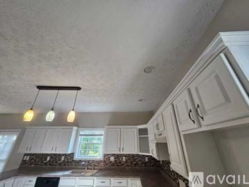 Louisville house for rent - A kitchen with white cabinets and a window above the sink.