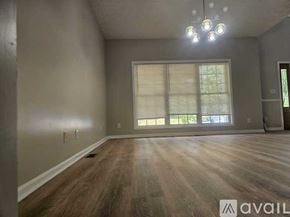 Louisville house for rent - A spacious room with wooden floors and a large window with blinds.