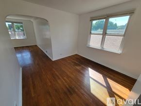 Chicago apartment for rent - A room with wooden floors and white walls, with a window and a view of trees outside.