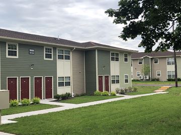 North Brunswick apartment for rent - a row of apartments with red doors and green grass and sidewalks
