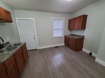 Lima apartment for rent - A kitchen with brown cabinets and a white door.