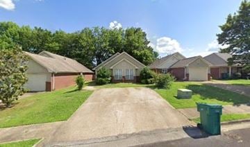 Tupelo house for rent - A residential area with houses and a green trash bin.