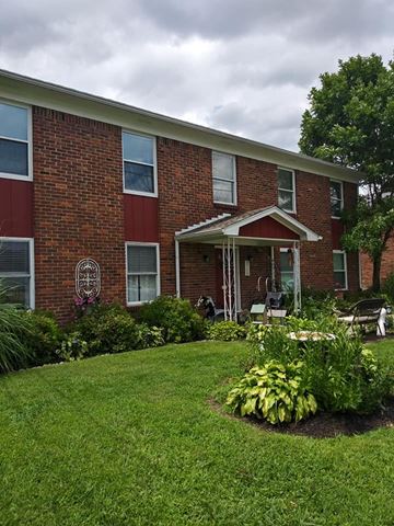Louisville apartment for rent - A red brick building with a white roof and a flower bed in front.