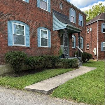 Louisville apartment for rent - A brick building with a green roof and a white door.
