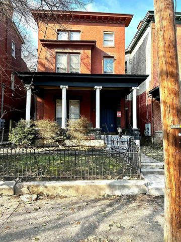 Louisville apartment for rent - A red brick house with a black iron fence in front.