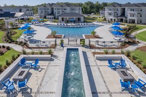 Fortson apartment for rent - A large swimming pool surrounded by blue lounge chairs and umbrellas.