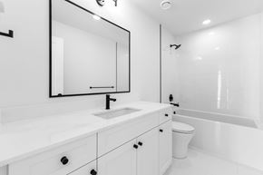 Langley house for rent - A white bathroom with a sink, mirror, and toilet.