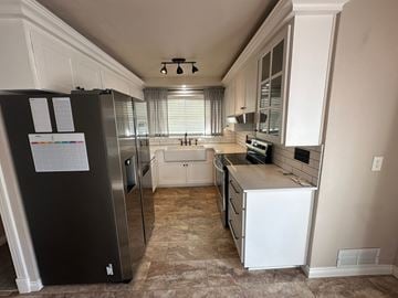 Sunnyside house for rent - A kitchen with a black fridge and white cabinets.