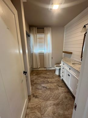 Sunnyside house for rent - A bathroom with a toilet, sink, and a window with curtains.