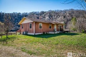 La Follette house for rent - A house with a brown roof and a yellow trim is surrounded by a grassy field.