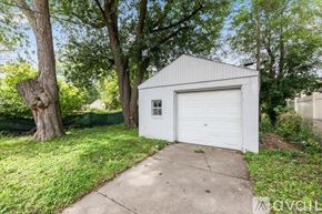 Hazel Park house for rent - A small white garage is situated on a concrete slab in a grassy area.