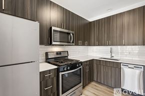 Chicago apartment for rent - A kitchen with a white refrigerator, black stove, and wooden cabinets.