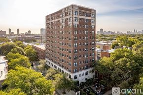 Chicago apartment for rent - A tall brown building with many windows is surrounded by trees.