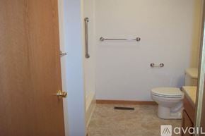 Tomah apartment for rent - A bathroom with a toilet, a towel bar, and a door.