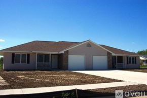 Tomah apartment for rent - A house with a brown roof and a white garage door is for sale.