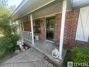 Axtell house for rent - A house with a red brick wall and a white porch.