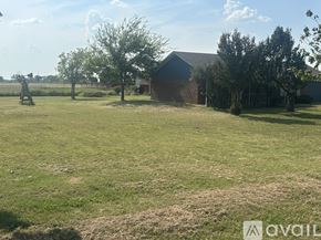 Axtell house for rent - A grassy field with a house and trees in the background.