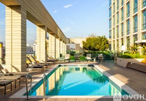 Los Angeles condo for rent - A pool surrounded by lounge chairs and a building in the background.