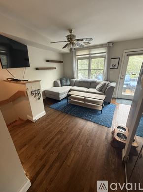 Boston condo for rent - A living room with a couch, a television, and a ceiling fan.