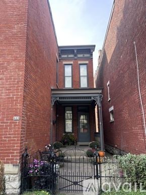 Newport house for rent - A black gate leads to a brick building with a balcony.