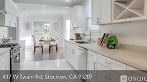 Stockton house for rent - A modern kitchen with white cabinets and a dining table set for four.