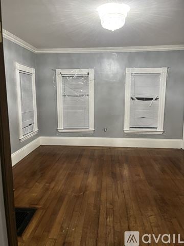 Brockton house for rent - A room with wooden floors and three windows.