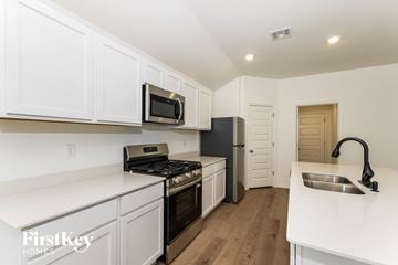 Oklahoma City house for rent - A kitchen with white cabinets and a black fridge.