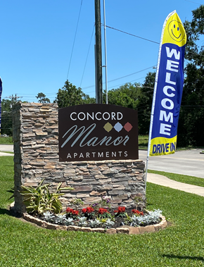 Beaumont apartment for rent - A welcome sign for Concord Manor Apartments is displayed in front of a stone wall.