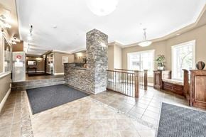 Calgary house for rent - A spacious lobby with a stone pillar and a black and white checkered floor mat.