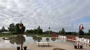 Calgary house for rent - A park with a pond, benches and a sign that says "Rocky Ridge".