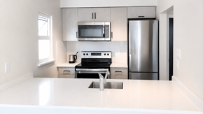 Vancouver apartment for rent - A modern kitchen with stainless steel appliances and white countertops.