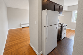 Vancouver apartment for rent - A white refrigerator is in the corner of a room with wood floors.