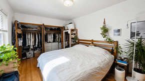 Vancouver apartment for rent - A bedroom with a large bed and a closet with clothes hanging.