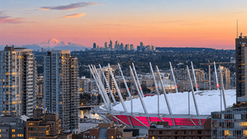 Vanvcouver apartment for rent - A cityscape with a large stadium in the foreground and a mountain in the background.