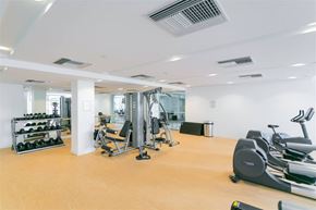 Vancouver apartment for rent - A gym with a variety of equipment including weights, a bench press, and a treadmill.