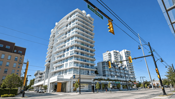 Vancouver apartment for rent - A tall white building with many windows is located at the corner of a street.