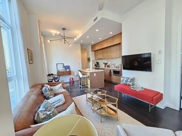 Vancouver apartment for rent - A living room with a brown leather couch and a red bench.