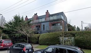 Vancouver apartment for rent - A black car is parked in front of a grey house with a tree on top of it.